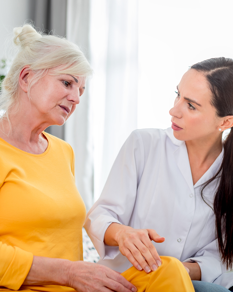 Nurse checking knee pain to senior female